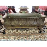 A heavily engraved decorative brass planter with lion mask handles on ornate feet,
