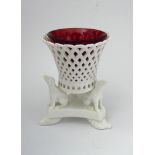 A Derby posy holder the pierced basket with red glass liner raised on three seated hounds,