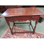 A circa 1800 pegged oak side table the planked top over a single frieze drawer and wavy apron on