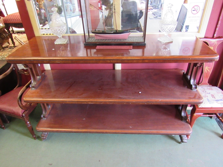 A large Victorian mahogany three-tier buffet with Gothic scroll supports between the shelves.