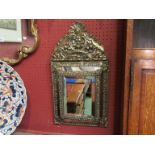 A 16th Century Style brass embossed cushion mirror with scroll,