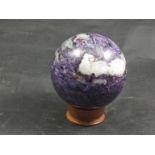 A Charoite sphere on wooden stand