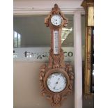 A Victorian carved light oak pendant barometer with clock and thermometer