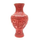 A large Chinese cinnabar lacquered vase of urn form, carved hillside village scenes with figures,