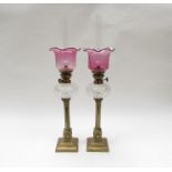 A pair of Victorian oil lamps, cranberry glass shade, cut glass reservoir,