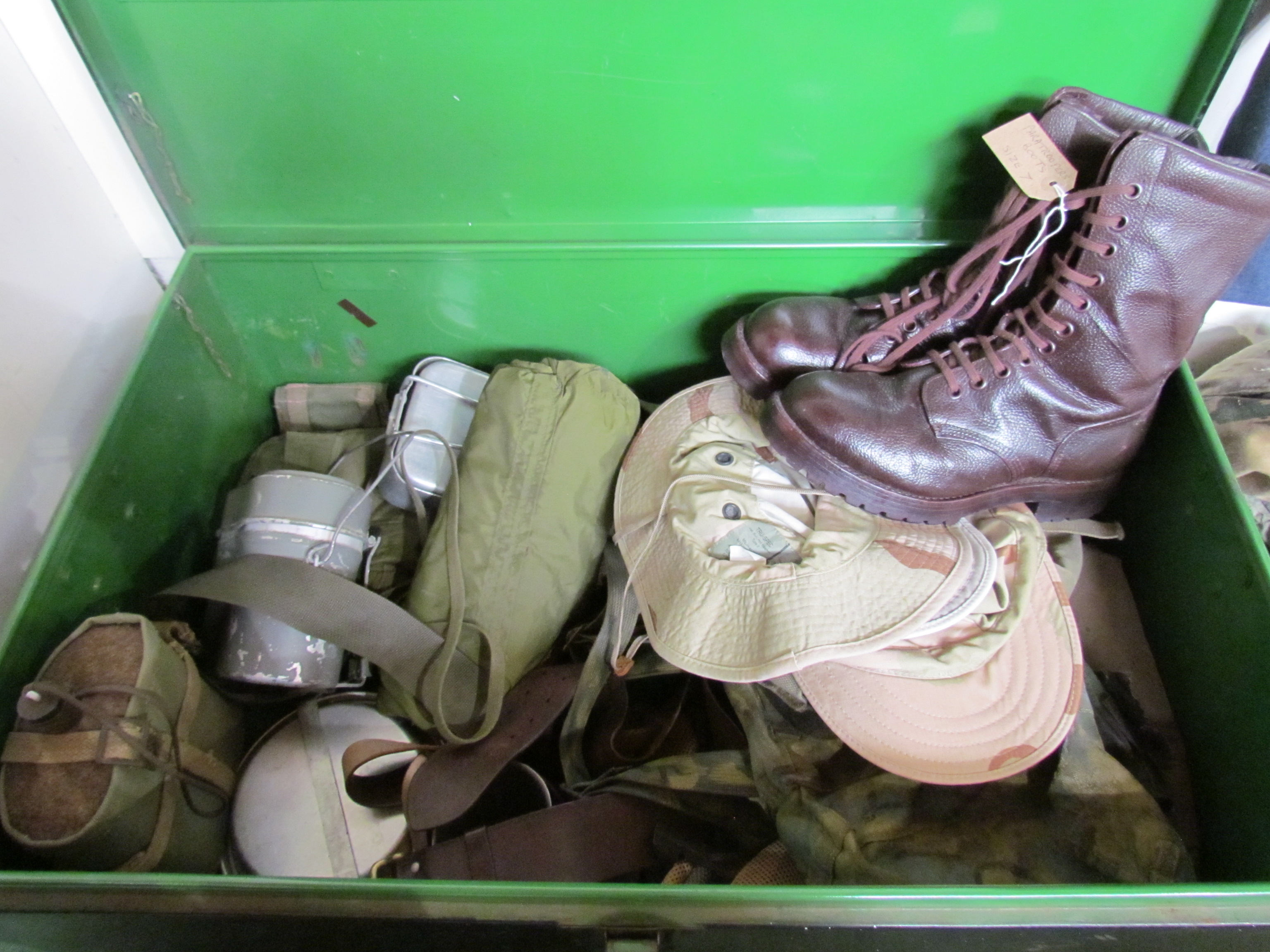 A metal trunk of military clothing including boots,
