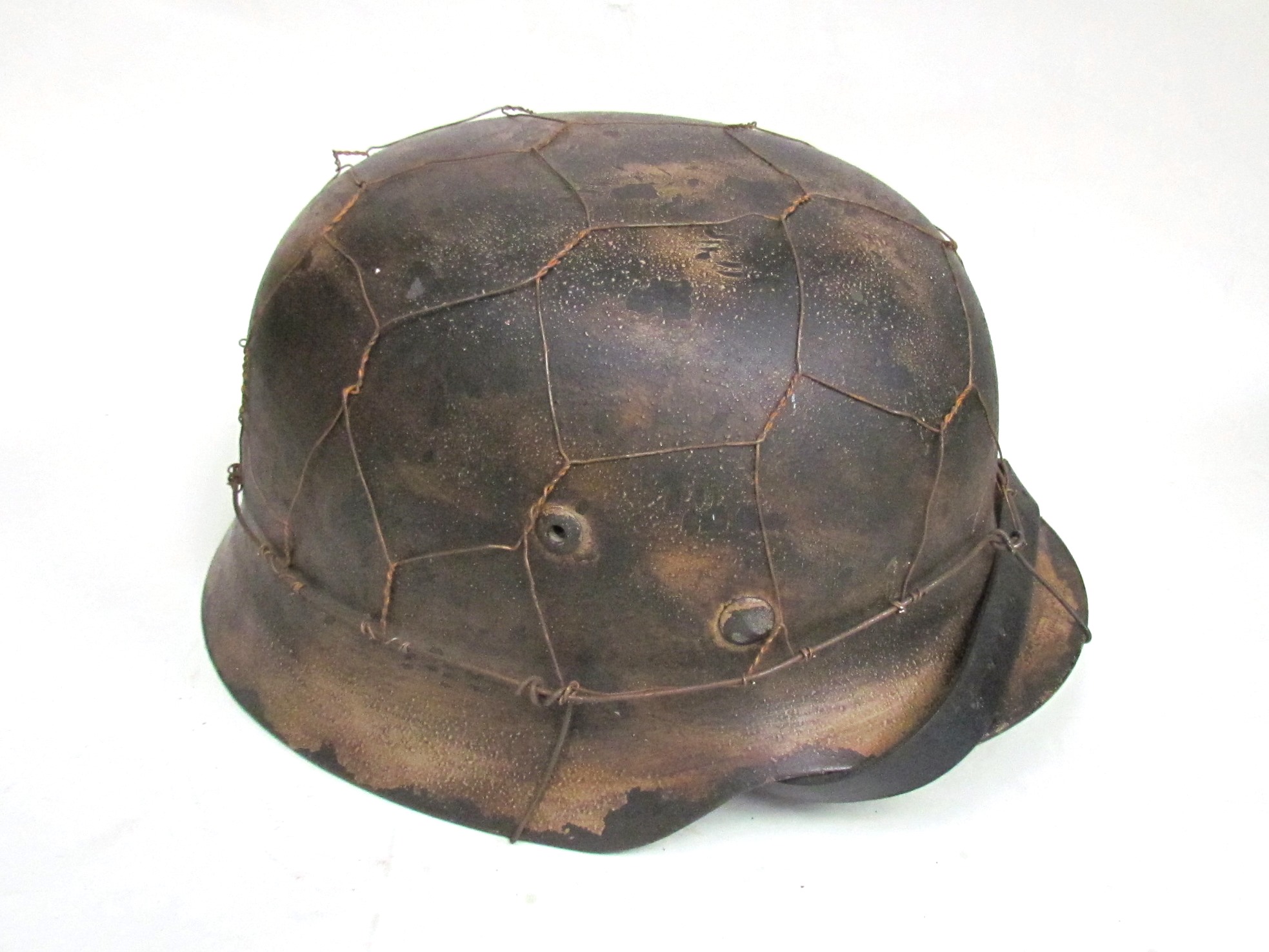A copy of a German M40 helmet with distressed tan paintwork and mesh covering