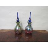 Two similar Okra style iridescent glass scent bottles with slender finial stoppers,