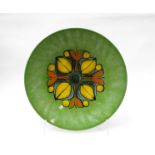 A large Poole Delphis charger in green with orange and yellow design,