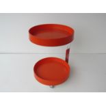 A two tier orange plastic table with chromed metal support, on castors.