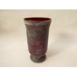 A large red glass vase with grey ash effect exterior.