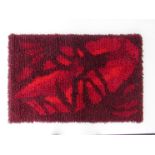 A Danish wool wall hanging with design in reds and oranges.