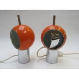 A pair of spherical orange adjustable metal table lamps on a chromed metal tubular base