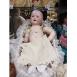 A wicker crib containing bisque head, composition body doll, 67cms, head stamped Jutta 1914 14½,