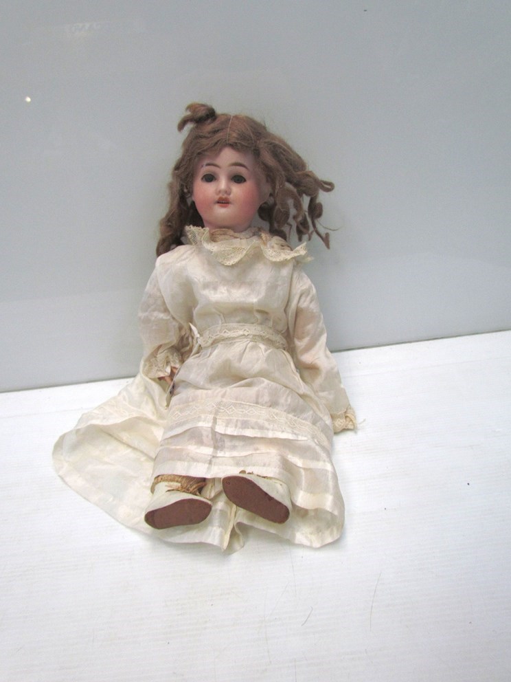 A bisque head, composition body girl doll in silk dress,