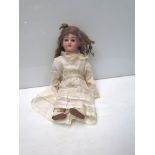 A bisque head, composition body girl doll in silk dress,