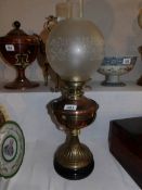 A brass oil lamp with black pottery base and acid etched shade