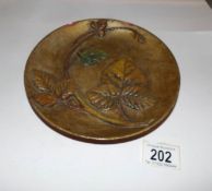 A Dr Christopher Dresser Linthorpe potters plate with moulded bramble leaf on gilt ground,