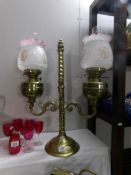 A brass twin font oil lamp with floral decorated later shades