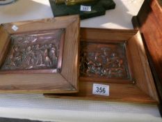 A pair of copper cherub plaques in pine frames