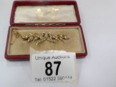 An Edwardian brooch with pearls fashioned as a ribbon (tested as gold) in original box