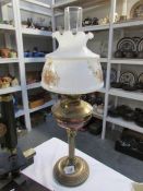 A brass oil lamp with floral decorated shade