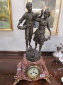 A mantel clock surmounted bronze figure