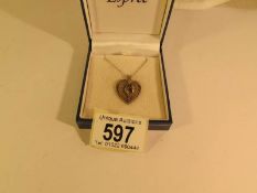 A silver pendant fashioned as a heart with sapphire set flowers to centre of pendant