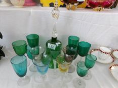 A green glass bell and a quantity of green and other coloured glass drinking glasses