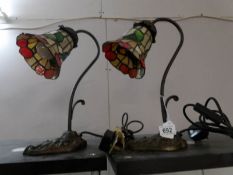 A matching pair of bronzed cast iron swan neck table lamps with leaded glass shades
