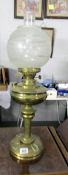 A brass oil lamp with etched glass shade