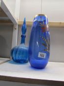A blue glass decanter and a blue glass vase