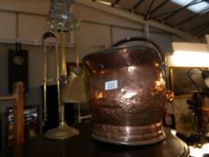 A copper coal scuttle and a brass companion set