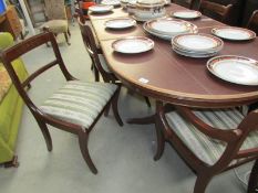An oval extending dining table with protective cover and a set of 8 brass inlaid dining chairs