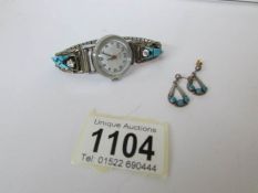 A Timex ladies wrist watch with silver shoulders and a pair of silver earrings