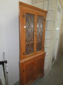 A light oak lead glazed corner cabinet