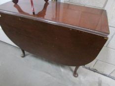 A mahogany drop leaf table on pad feet