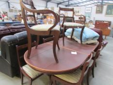 An extending mahogany dining table with protective cover and 8 brass inlaid dining chairs