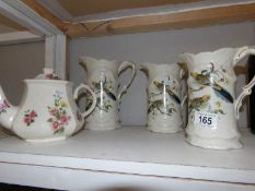 A set of 3 graduated Staffordshire jugs decorated with birds and a teapot