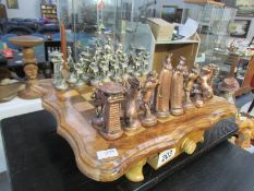 A metal chess set on a wooden board
