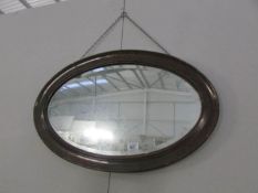 An oval bevel edged mirror in oak frame,