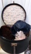 A vintage circular hat box with floral writing together with 2 vintage hats and a pink feather