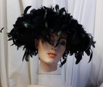 A large brimmed black hat with decorative feather decoration