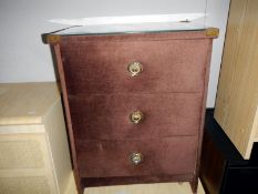 A brown fabric covered glass topped bedside chest