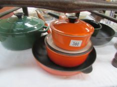 A quantity of Le Creuset pots and pans including orange, green,