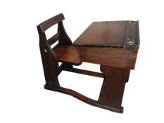 An Edwardian oak child's desk with combined folding chair and ceramic castors,