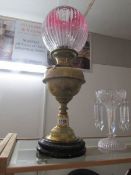 A brass oil lamp on pot base and complete with shade and chimney