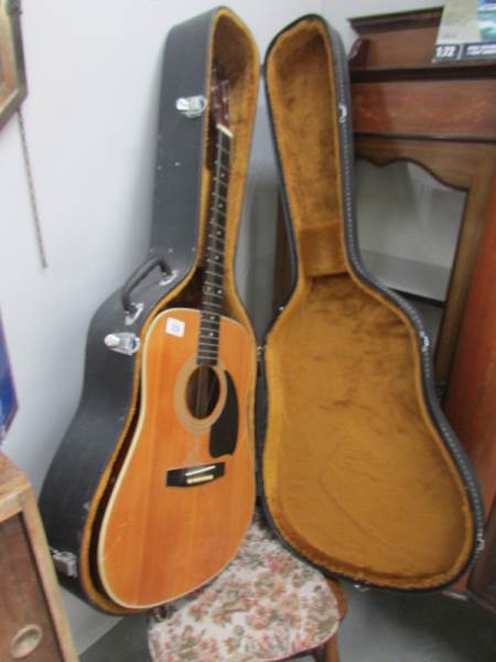A cased Arbor acoustic guitar