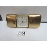 An Estyma engine turned gold plated cushion cased travel clock