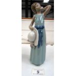 A Lladro figurine of a girl holding a hat